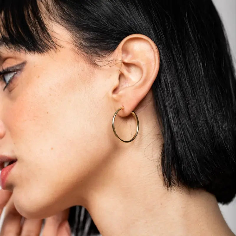 Close-up of a woman wearing 14K Gold Hoop Earrings 25mm.