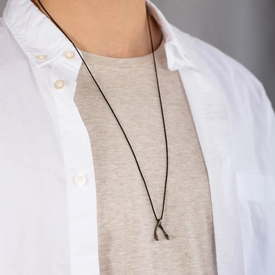 Wishbone Necklace Oxidized Silver 925 on black cord, worn by a person in casual attire