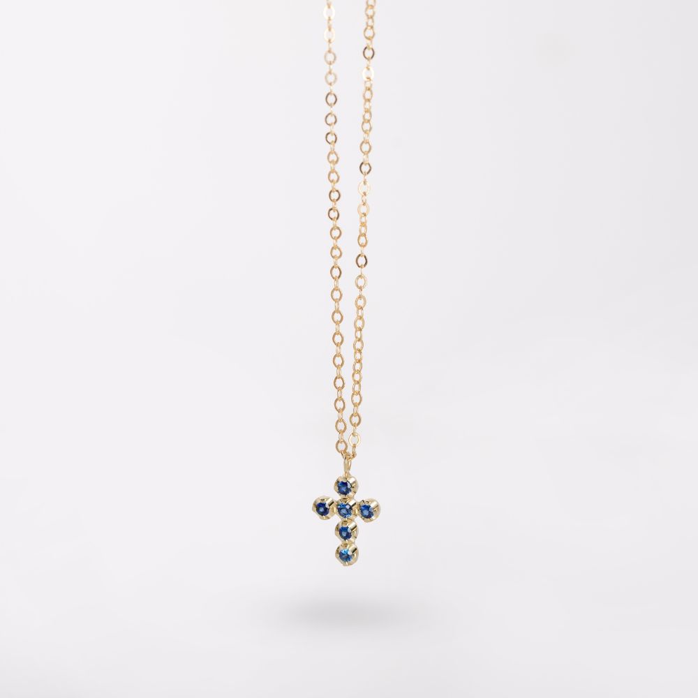 Blue sapphire 14K gold cross necklace with vibrant gemstones on a delicate chain, symbolizing elegance and faith.