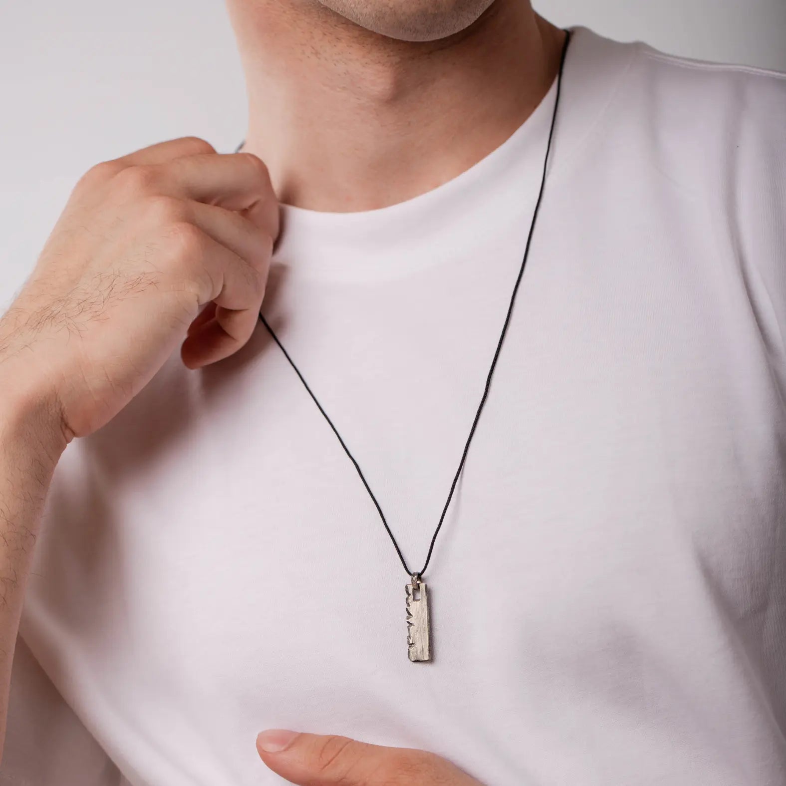Model wearing personalized oxidized sterling silver necklace vertical bar pendant on white shirt