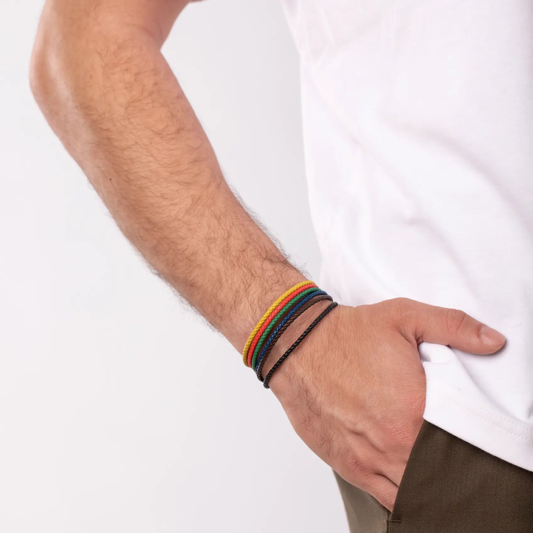 Man wearing a colorful stack of bracelets, hand in pocket, depicted against a plain background.