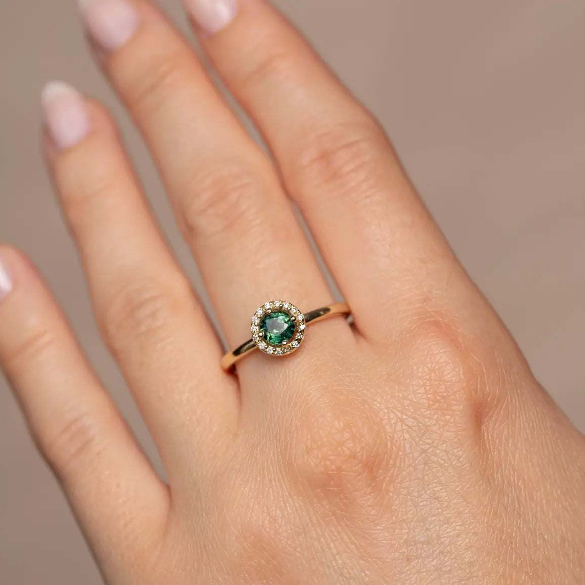 14K Halo Engagement Ring Green Sapphire Diamond on hand, featuring art deco design with a green sapphire center and surrounding diamonds.