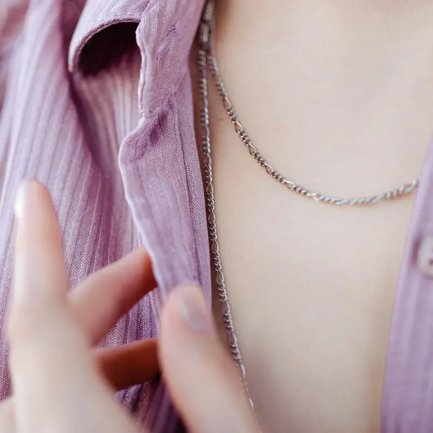 Person wearing Figaro Chain Silver 925 necklace over a purple shirt, showcasing the elegant silver design.