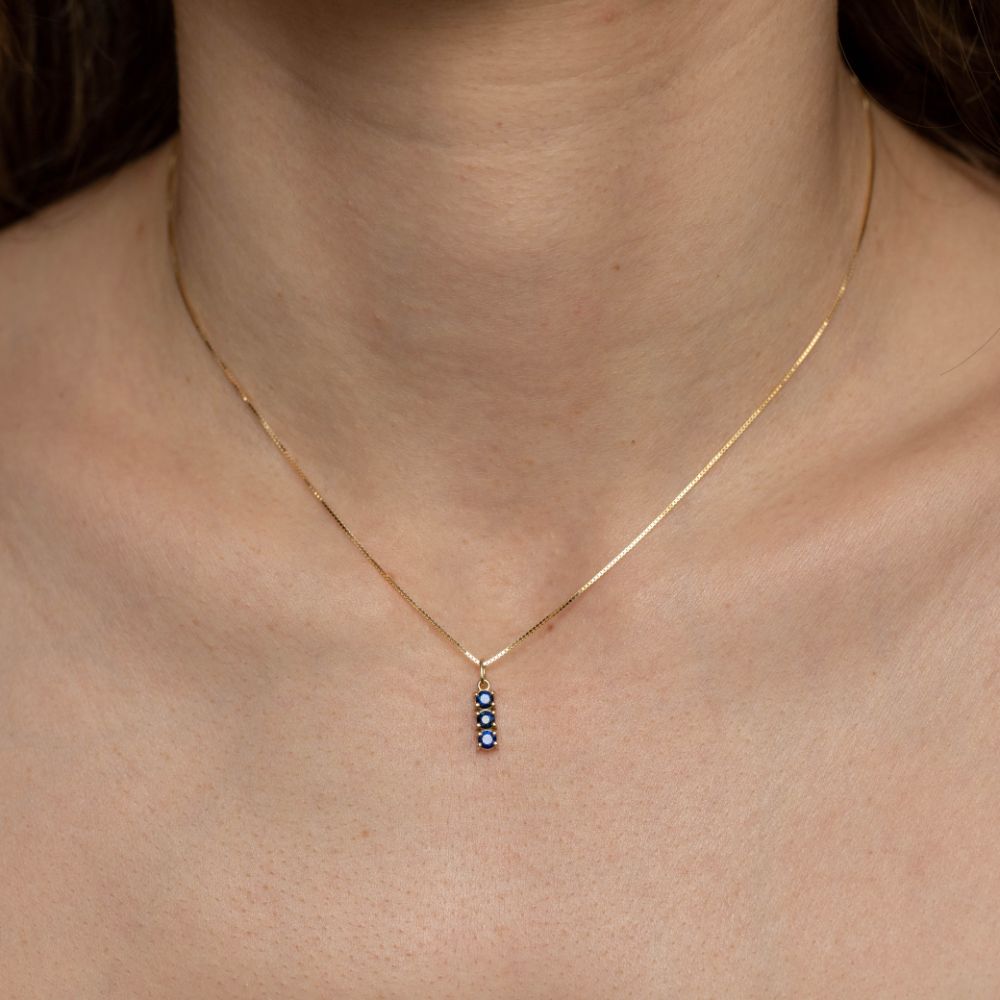 Woman wearing 3 blue sapphire necklace 14K gold, vertical bar setting, showing delicate style and craftsmanship.