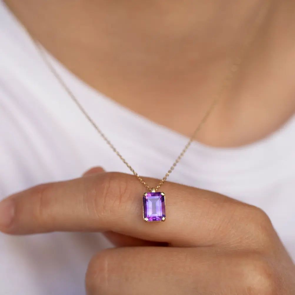 Person wearing Amethyst Necklace 14K Gold Octagon Cut with purple gemstone on a gold chain, highlighting elegant gift packaging.
