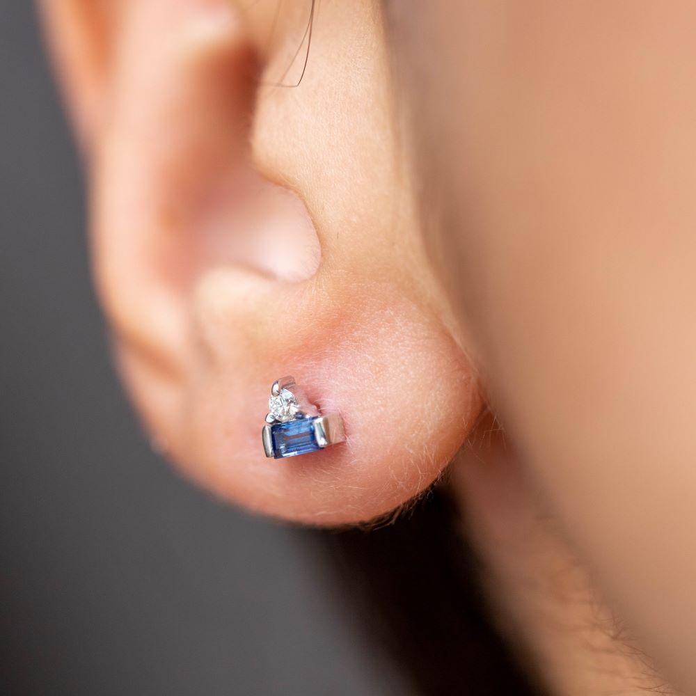 Close-up of ear wearing Blue Baguette Sapphire Diamond Studs 14K in white gold, featuring sapphires and diamonds.