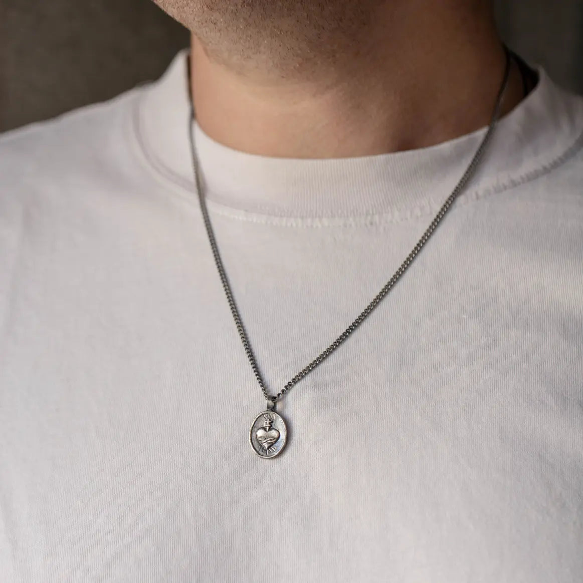 Sacred Heart Necklace Oxidized Silver on a 60cm curb chain, unisex sterling silver pendant, hand carved, displayed on a white t-shirt.