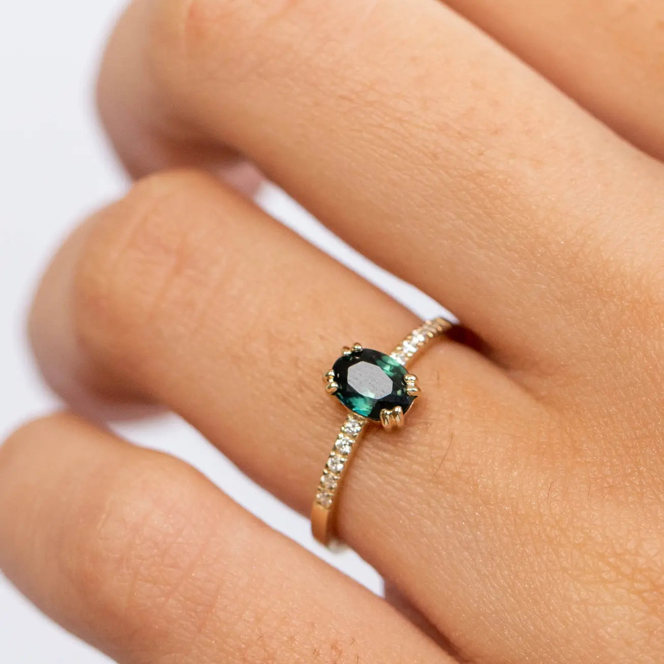 Diamond Teal Blue Sapphire Engagement Ring on hand, featuring a teal blue sapphire and brilliant diamonds set in 14K gold.