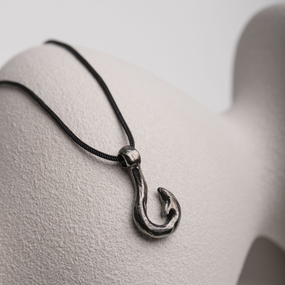 Fishhook Pendant Necklace Oxidized Silver with black cord on white background.