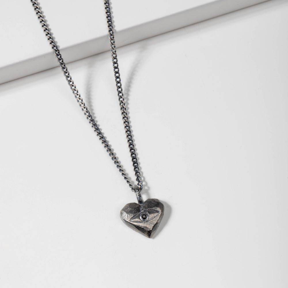 Oxidized silver heart necklace with black diamond on a white background.