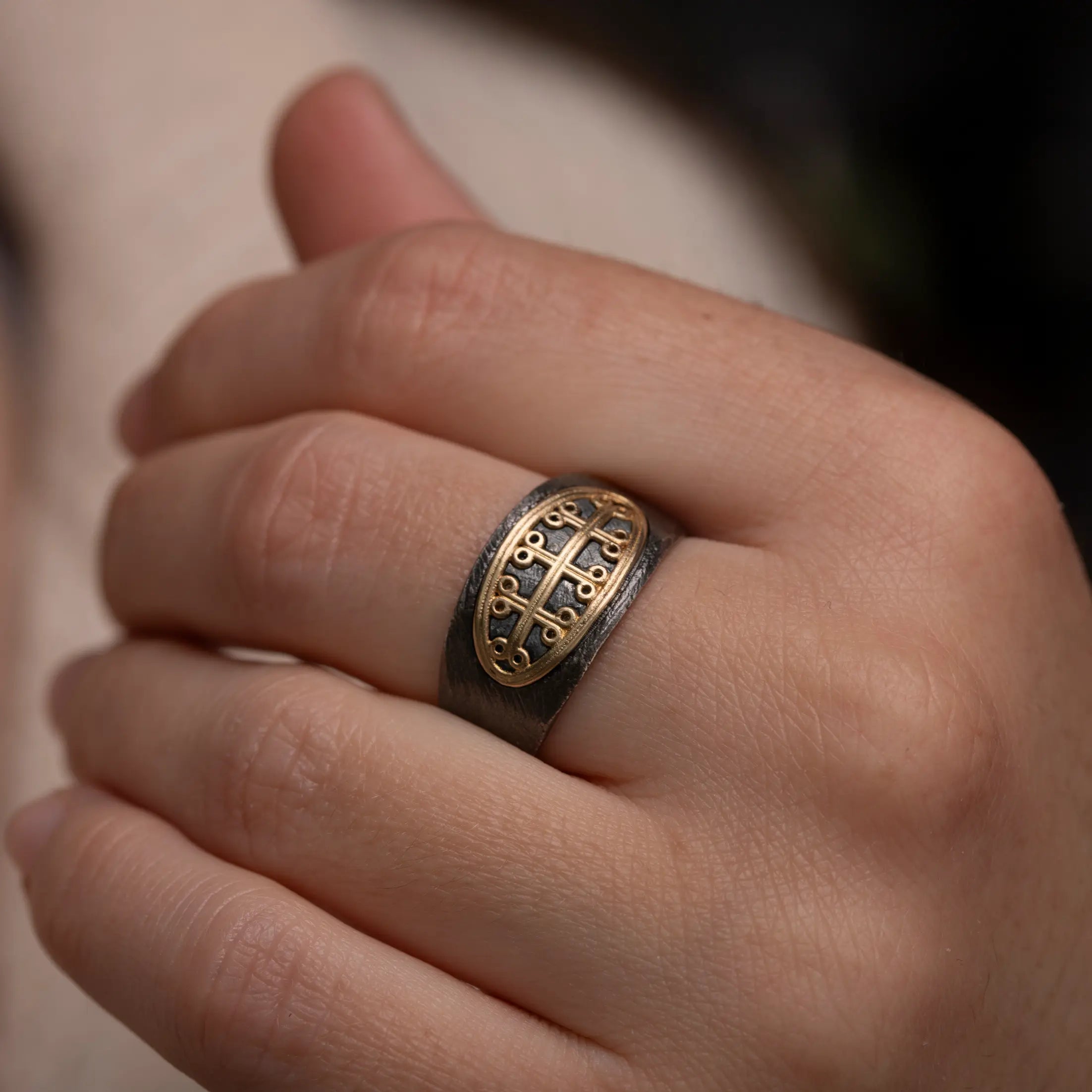 Close-up of a hand wearing a Signet Ring 14K Gold & Silver 925 Oval with a textured surface.