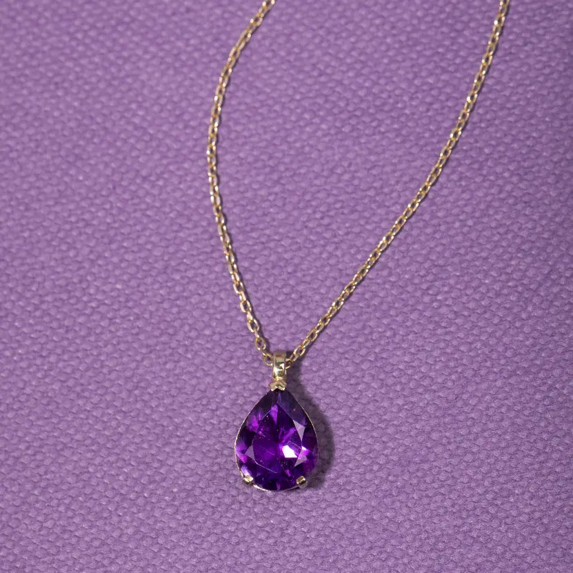 14K Gold Purple Amethyst Necklace Pear Cut on textured purple background.