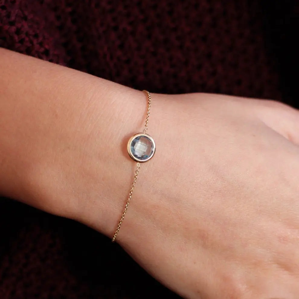Elegant 14k gold blue topaz bracelet on wrist, featuring a natural 10mm blue topaz gem, ideal for gifts and special occasions.