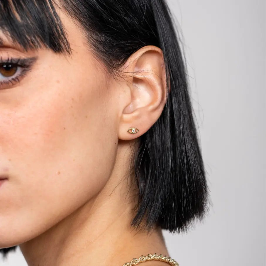 Woman wearing Evil Eye Diamond Studs 14K made of gold and diamonds, styled elegantly for a sophisticated look.