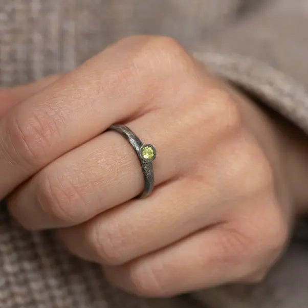 Handcrafted oxidized 925 silver ring with peridot gemstone, presented on a finger, showcasing its brutalist design.