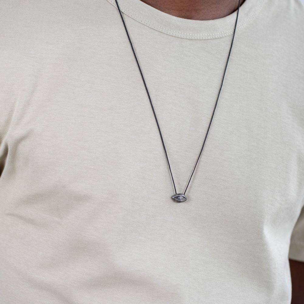 Man wearing Evil Eye Necklace Oxidized Silver 925 London Blue Topaz on plain shirt, showcasing black oxidized sterling silver pendant.