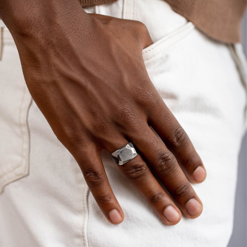Wide Ring Oxidized Silver Faceted worn on a man's hand, featuring a black oxidized finish and brutalist design, 13mm width.