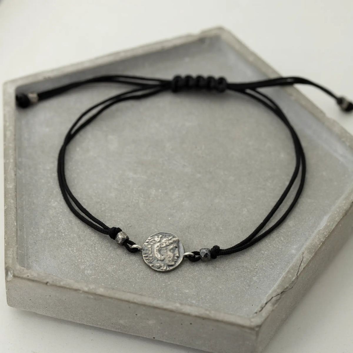 Alexander the Great oxidized silver bracelet with adjustable black cord on gray display tray