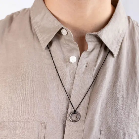 Man wearing Circle Necklace Oxidized Silver 925 with black cord, showing minimalist design on neutral shirt.