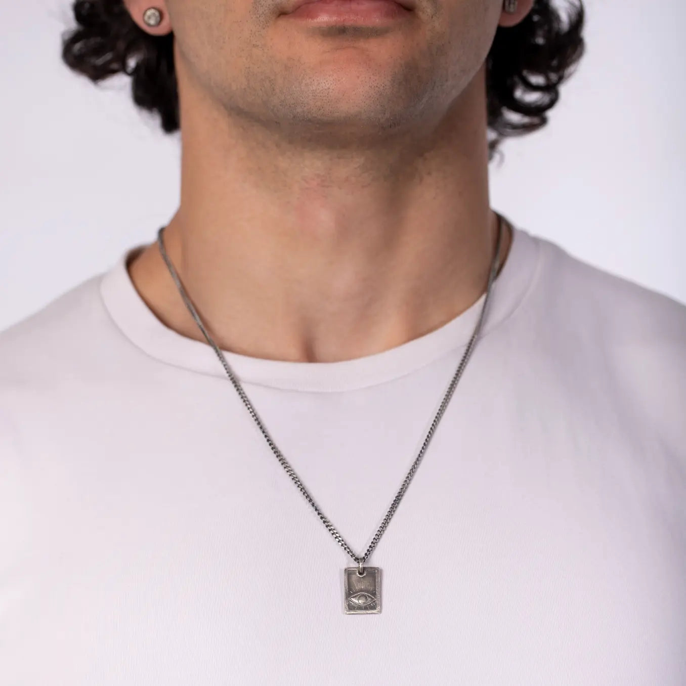 Eye Necklace Oxidized Silver 925 worn by a man, featuring a handcrafted eye on a rectangle tag with a black oxidized sterling silver curb chain.