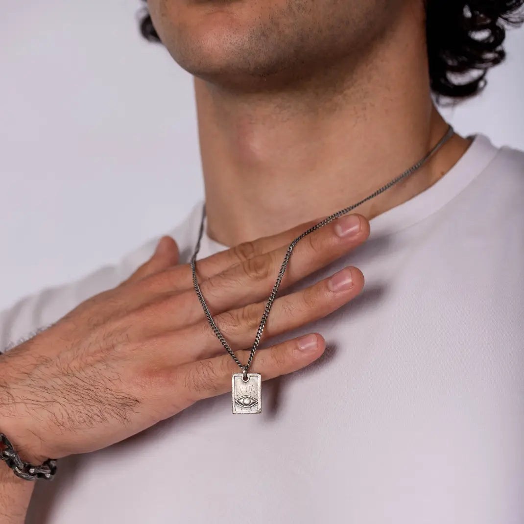 Man wearing Eye Necklace Oxidized Silver 925 with handcrafted eye on a rectangle tag and black oxidized curb chain.