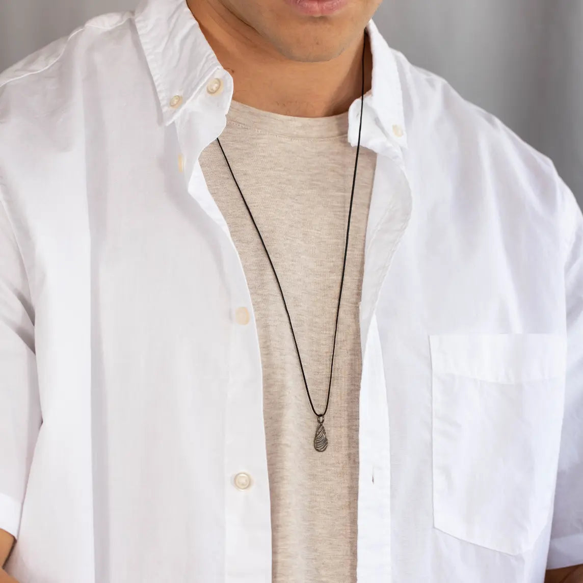 Man wearing Wavy Pendant Necklace Oxidized Silver on white shirt, showcasing handmade sterling silver jewelry gift for men.
