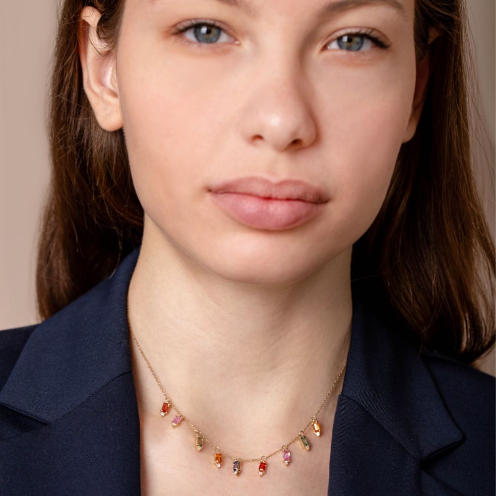 Woman wearing Dangle Necklace Sapphire Diamond 14K Gold with colorful gemstones.