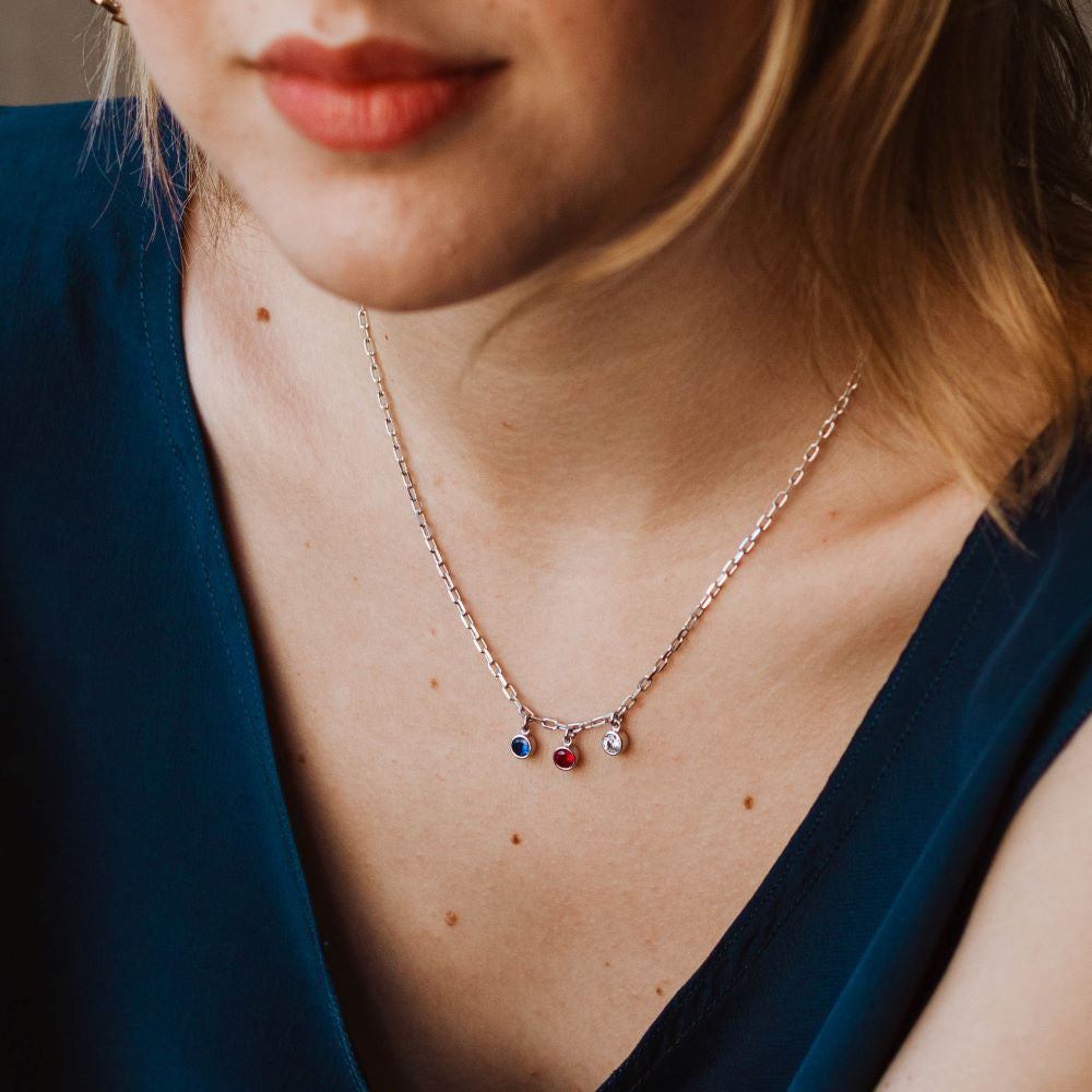 A close-up of a woman wearing a Birthstone Personalized Necklace Silver 925 with colorful cubic zirconia stones.