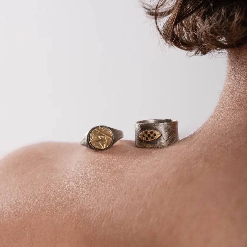 Elegant gold and silver men’s jewelry rings on shoulder, showcasing mixed metal style