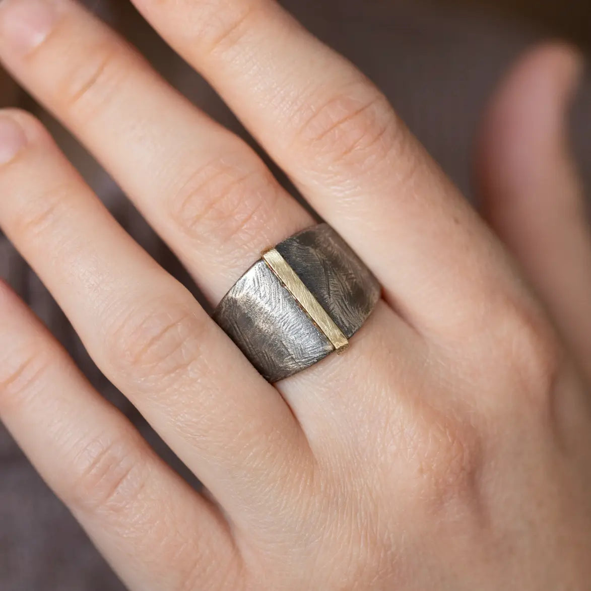 Close-up of a hand wearing a 14K Gold & Oxidized Silver 925 Ring with a handcrafted design and raw texture.