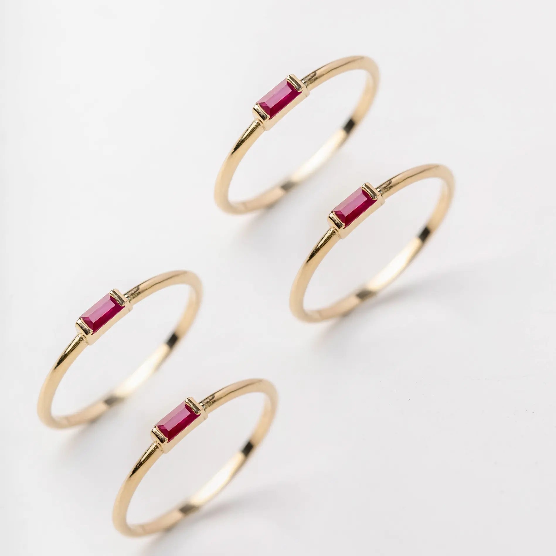 gold rings with red rubies on a light gray background